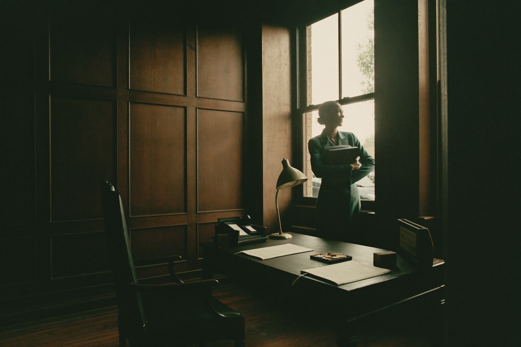 A quiet panelled study at dawn; a closed ledger held at the window